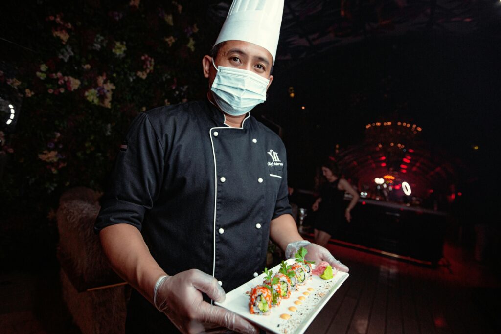 A professional chef in Dubai presents a platter of vibrant sushi rolls at a luxurious restaurant setting.